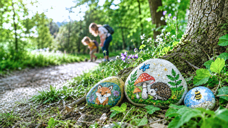 Enfant découvrant un galet peint dans un parc